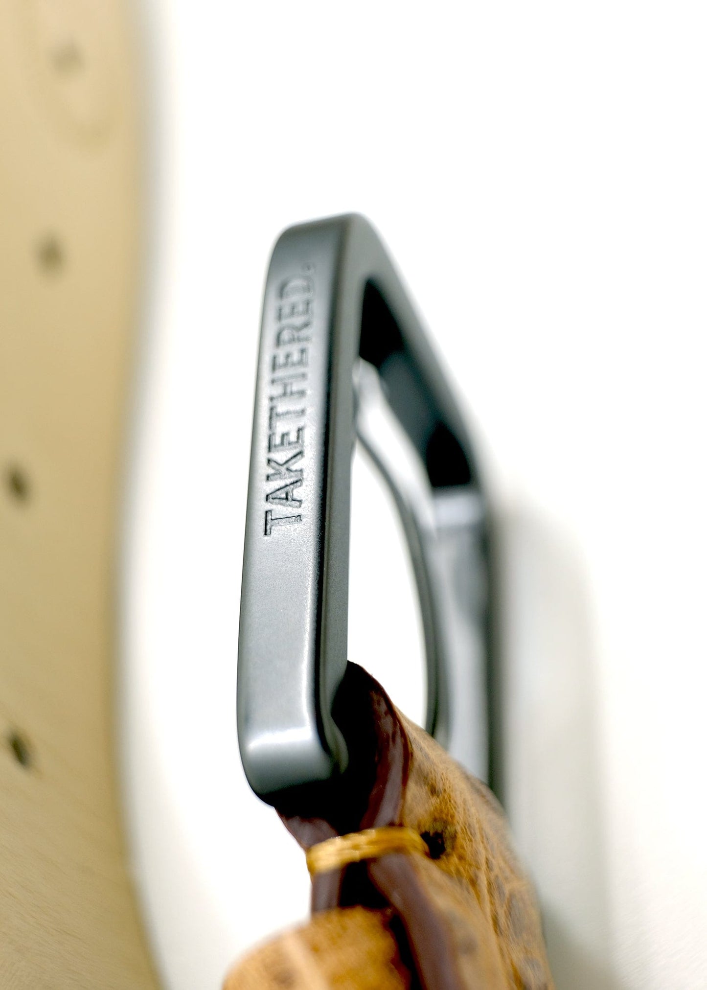 Side view of the tan Mississippi Belt buckle in matte black, engraved with the "TAKETHERED" brand name.