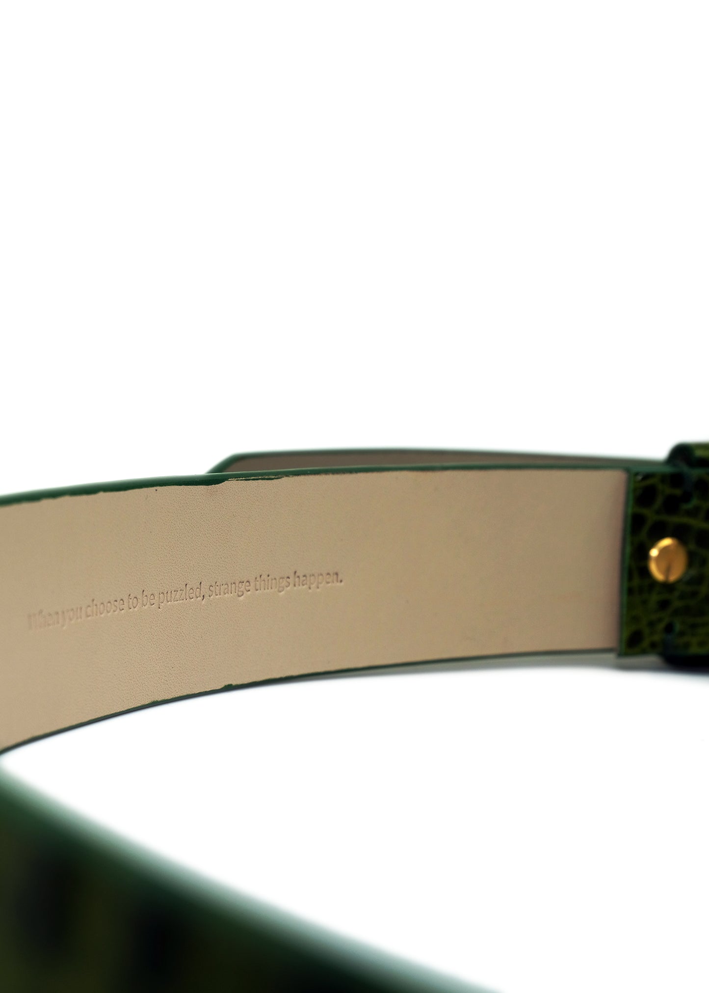 Interior view of the Atomic Green belt showing the hidden embossed text: "When you choose to be puzzled, strange things happens".