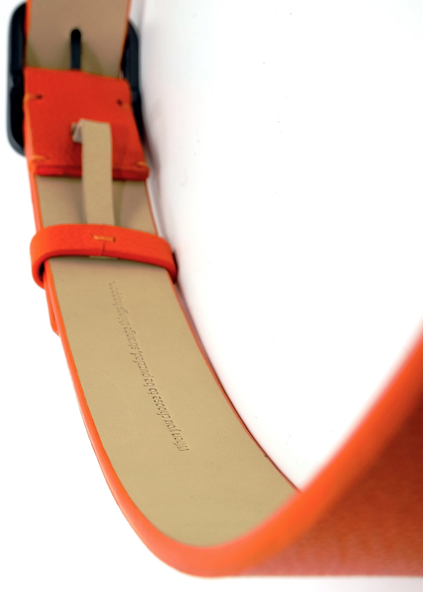 Interior view of an orange belt with the hidden embossed text "When you choose to be puzzled, strange things happen."