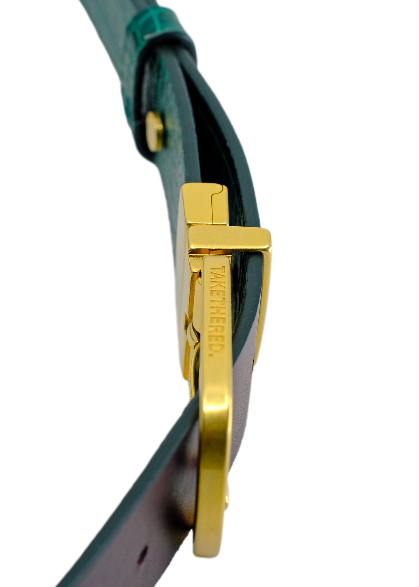 Side-angle macro of the Two-Face belt, focusing on the gold-tone reversible buckle's swivel joint and engraved branding.