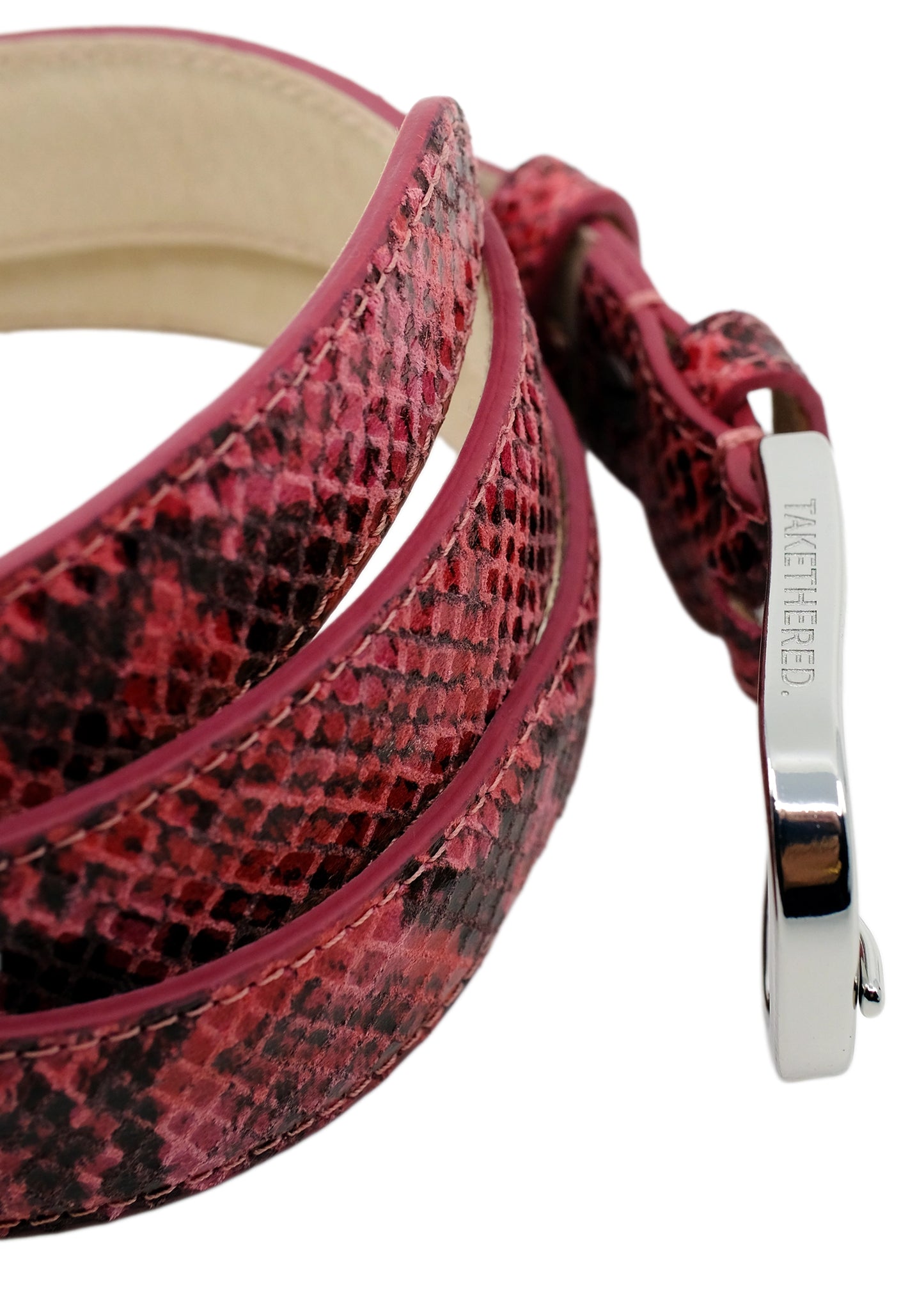 Extreme high-angle macro of the Barbie Pink snakeskin belt, focusing on the polished silver buckle and branding.