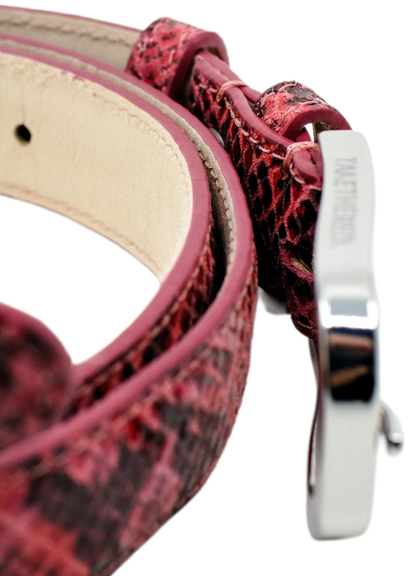 Extreme high-angle macro of the Pink snakeskin belt, focusing on the polished silver buckle's top edge and branding.