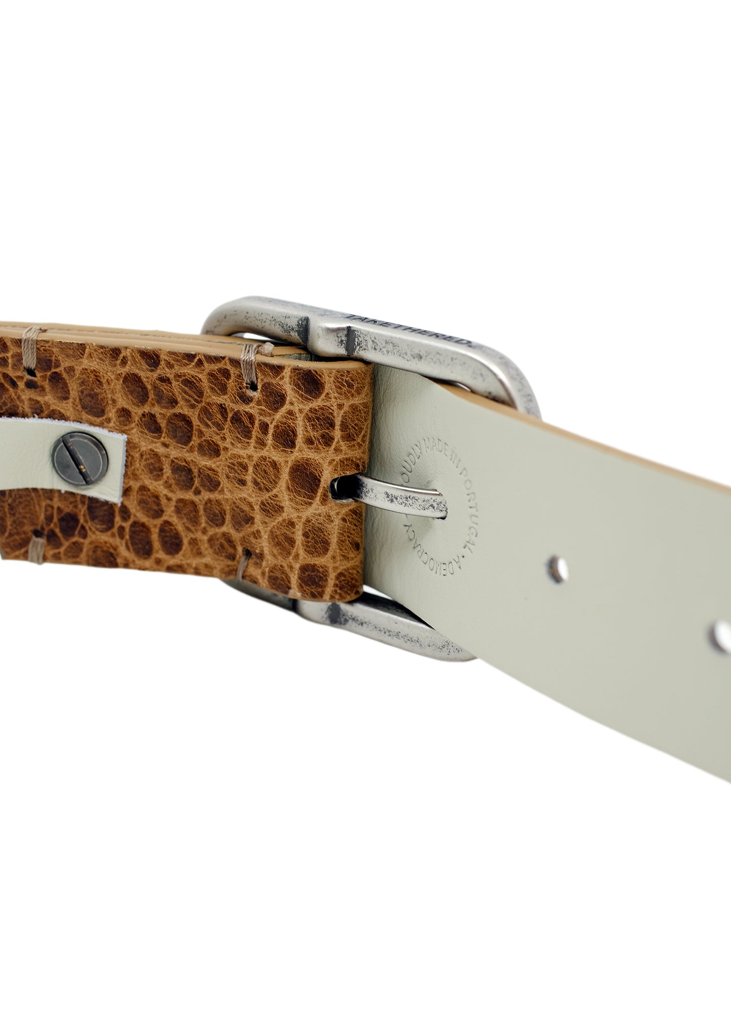 Close-up of the Dusty Spring belt's weathered silver buckle attachment, featuring the "Proudly Made in Portugal" branding on the inner lining.