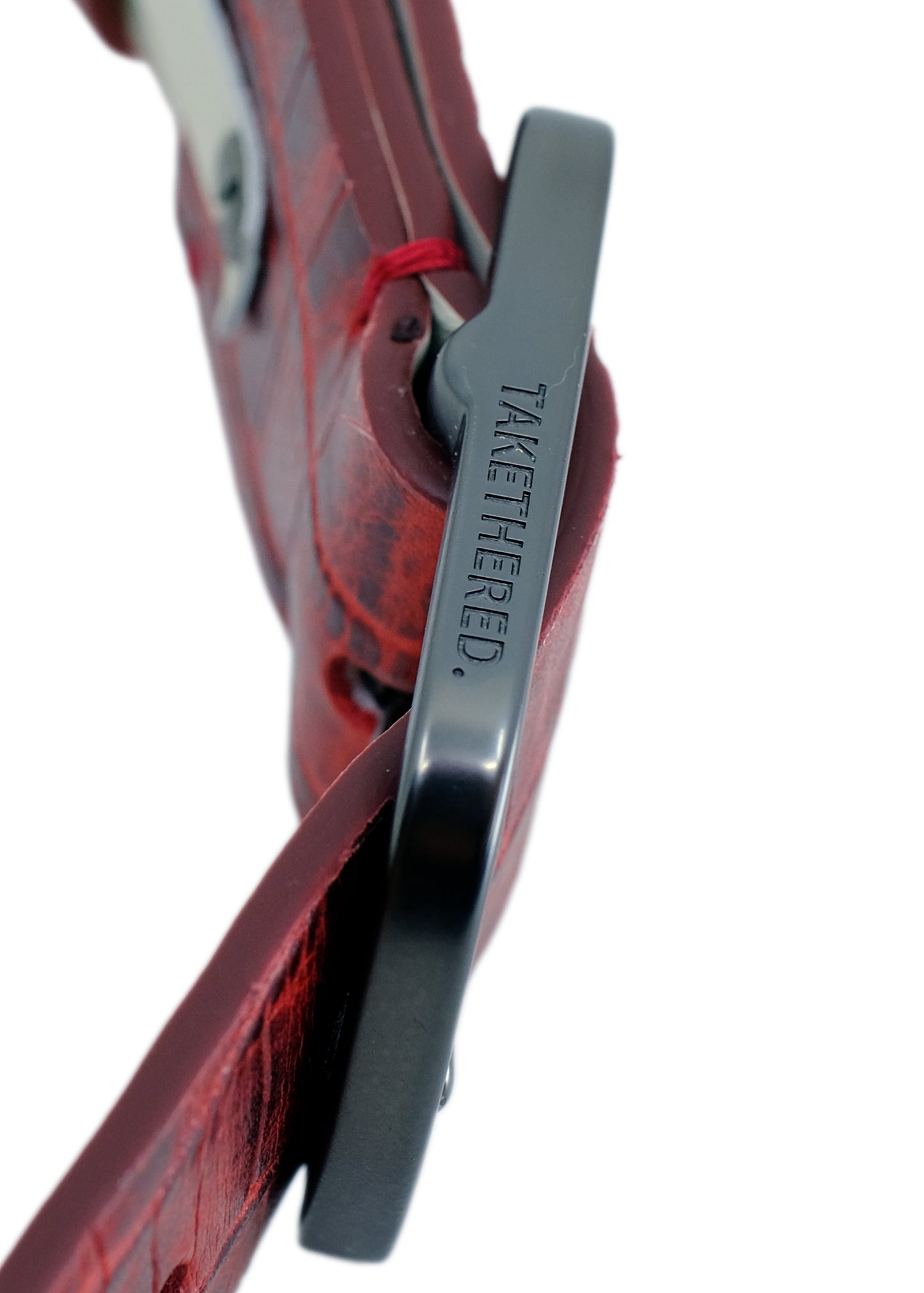 Extreme side-angle macro of the Pink Grape belt, focusing on the branding on the sleek black dull brass buckle.