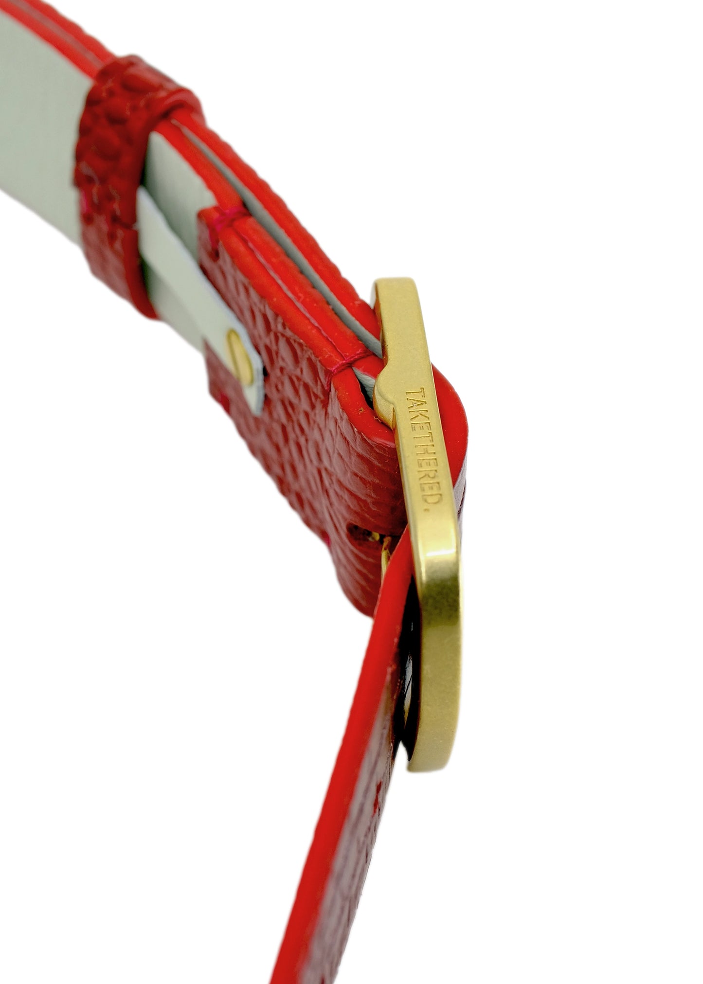 Side-angle macro of the Dry Blood belt, focusing on the gold buckle's engraved branding and the vibrant red alligator-style leather texture.