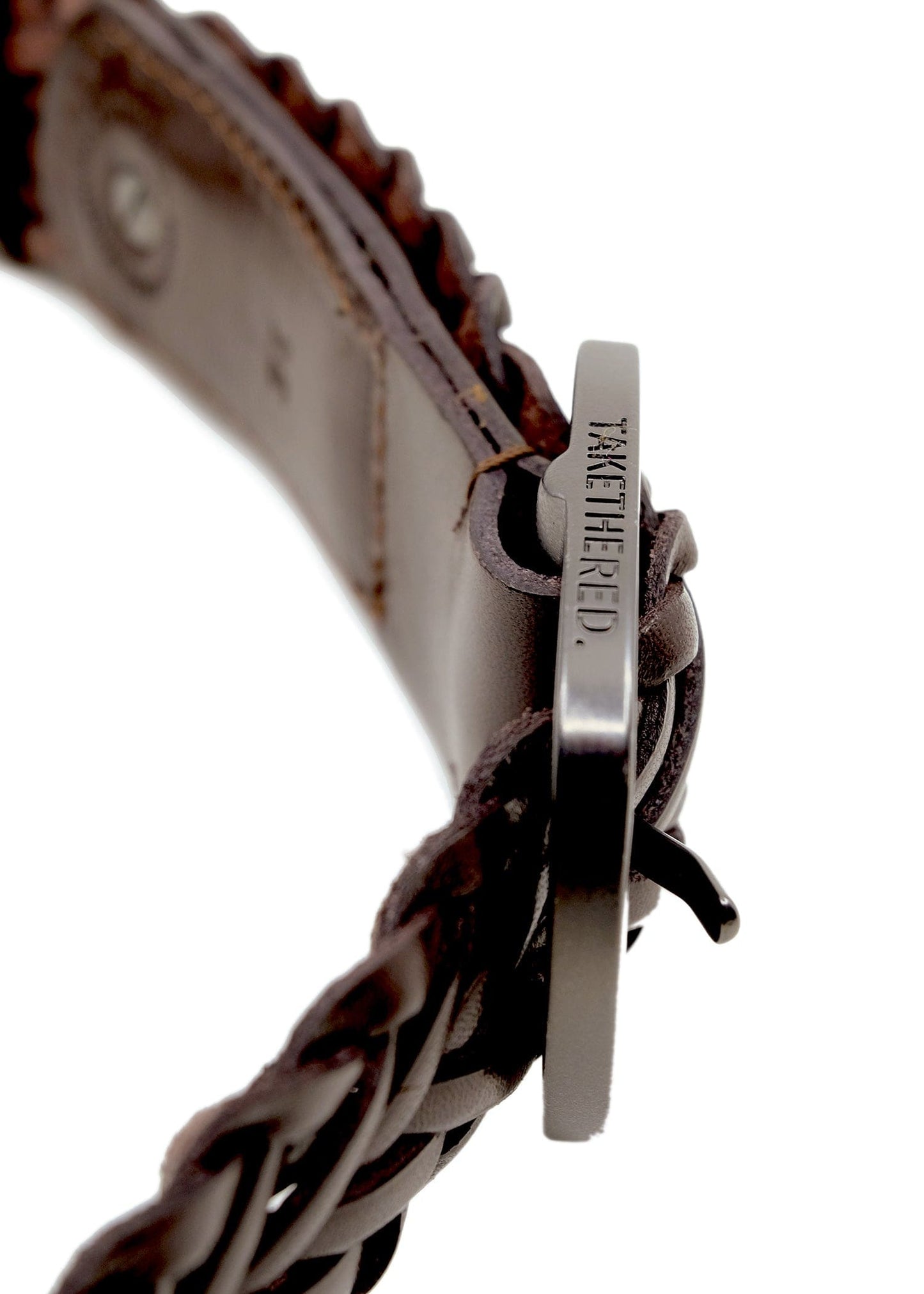 Macro shot of Espresso braided leather belt showing the side of the matte black buckle with "TAKETHERED." engraving.