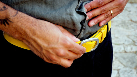 Close-up of a man's waist wearing a submarine yellow leather belt with a silver buckle embossed with TakeTheRed.