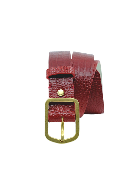 Vertical profile of the Dry Blood alligator embossed belt, coiled to showcase the golden buckle and the deep red texture.