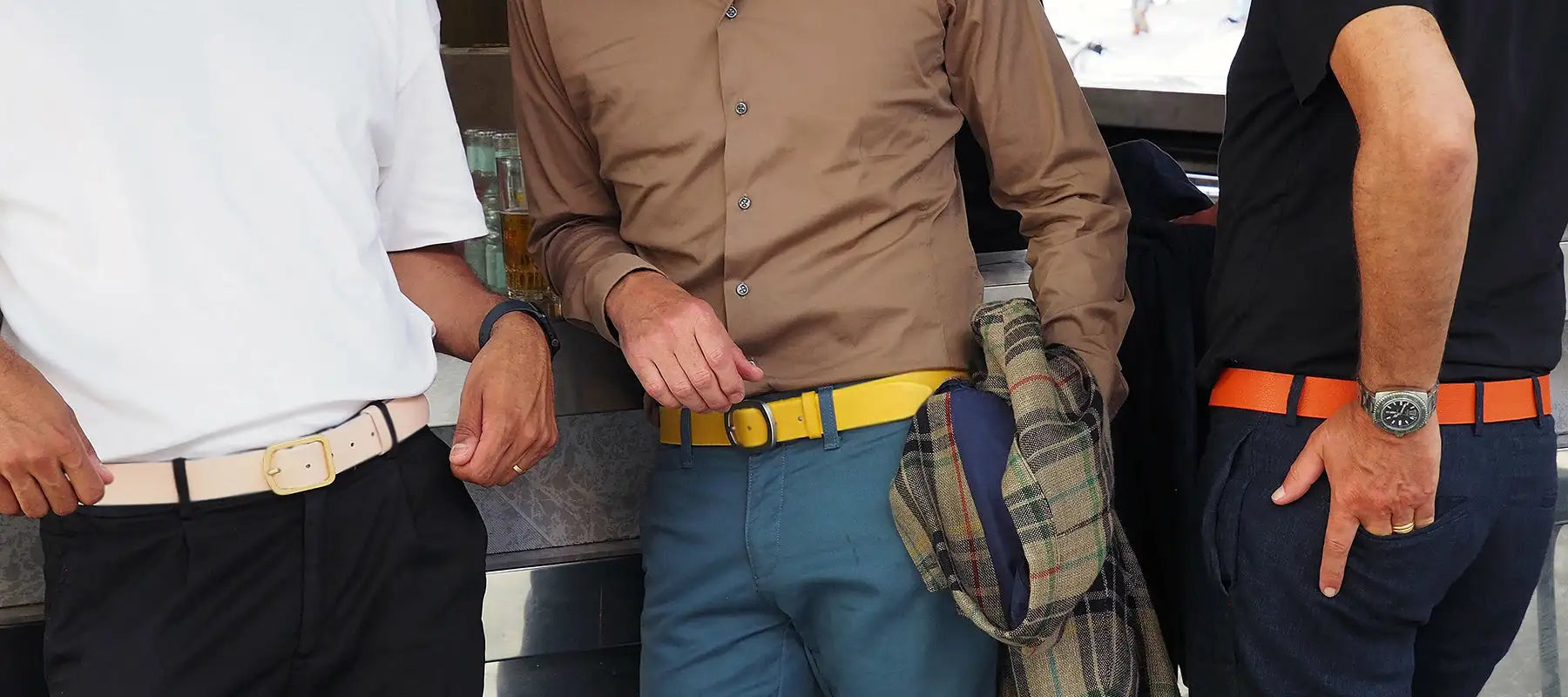 Close-up lifestyle picture of three men wearing the smooth classic leather belt in pink, yellow and orange