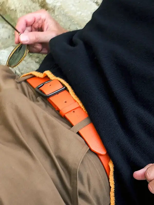 A macro lifestyle shot of a classic Tatooine sunset orange leather belt with black buckle.