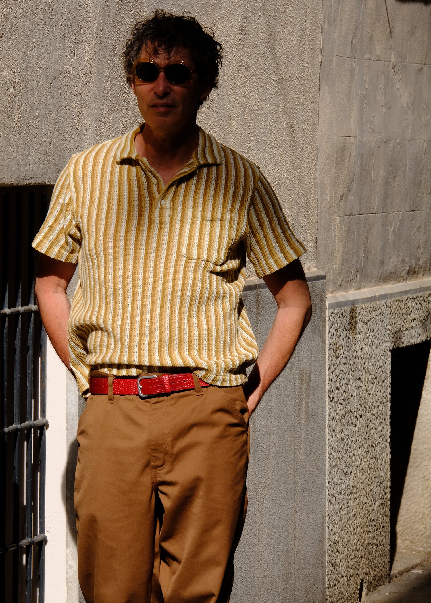 Lifestyle shot of the croc-embossed Blood Simple belt worn with brown trousers and a yellow striped shirt.